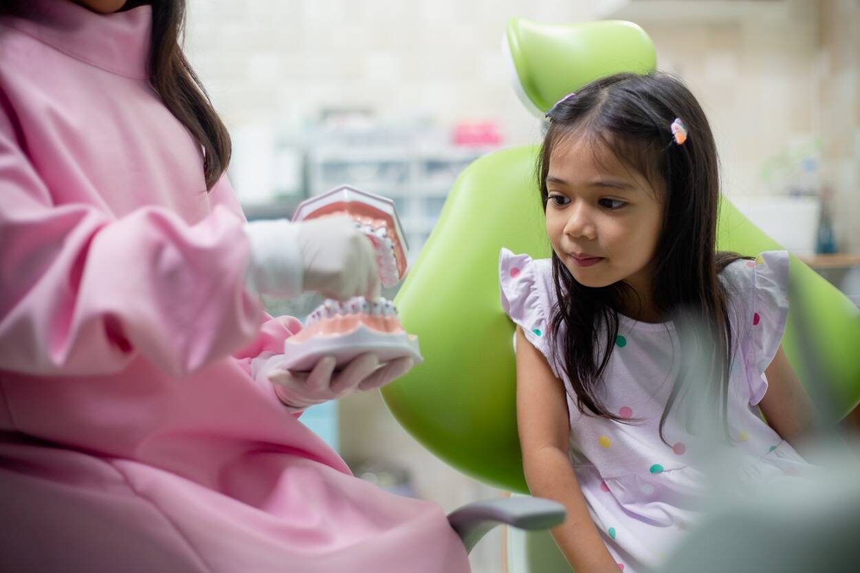 Young girl learning about dental care during a pediatric dental visit.