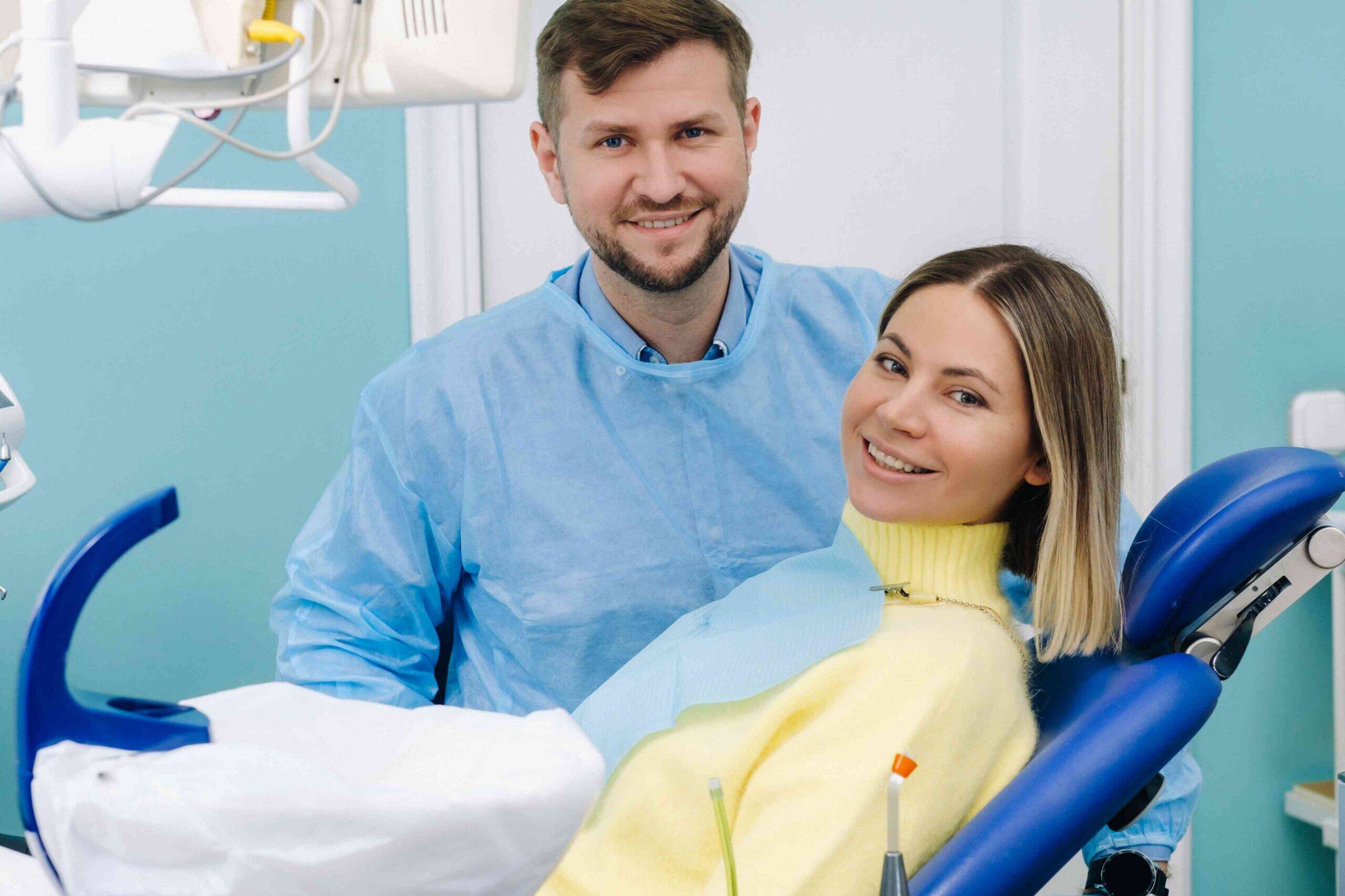 Smiling patient seated in a dental chair with a dentist in a clinic.
